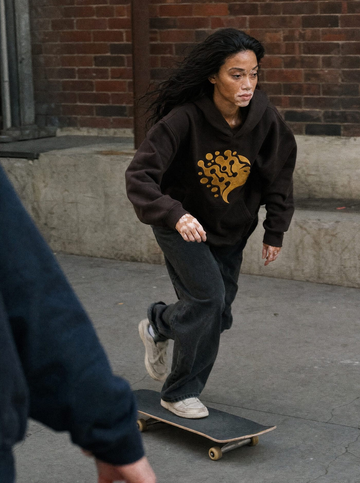 Vitilia en skate dans la rue, hoodie brun. Image générée par IA.